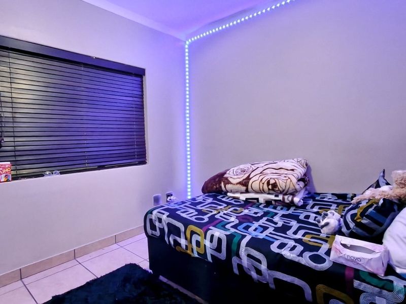 A bedroom featuring tiled flooring and venetian blinds, illuminated by integrated LED strip lighting.