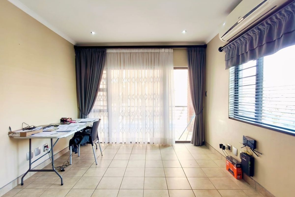 A bright living area featuring tiled flooring, recessed lighting, an air conditioning unit, and a sliding door leading to an outdoor space.