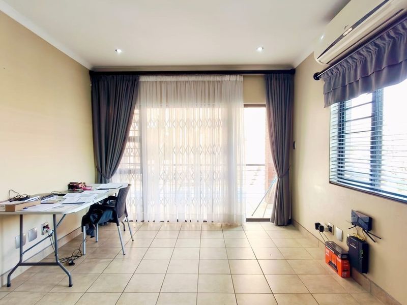 A bright living area featuring tiled flooring, recessed lighting, an air conditioning unit, and a sliding door leading to an outdoor space.