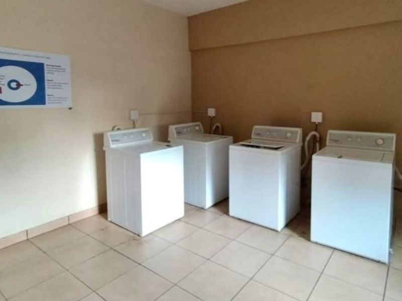 A functional communal laundry area featuring tiled flooring and multiple washing machine connections.