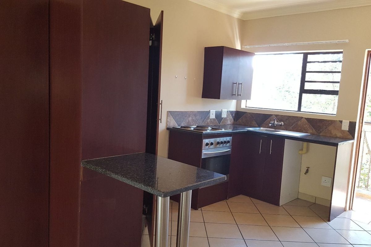 A functional kitchen featuring dark wood cabinetry, granite countertops, an integrated stove and oven, and tiled flooring with an adjacent breakfast bar.