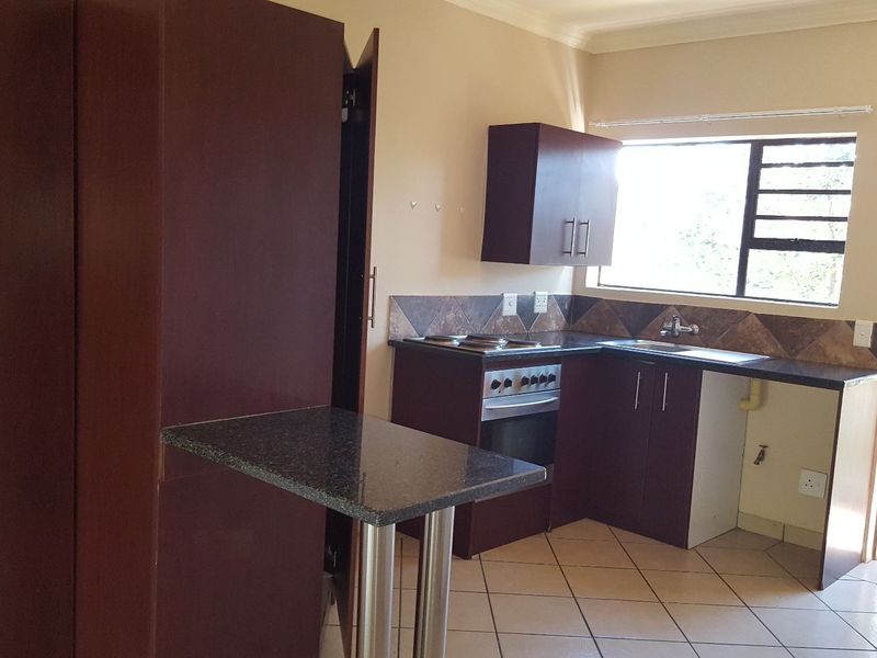 A functional kitchen featuring dark wood cabinetry, granite countertops, an integrated stove and oven, and tiled flooring with an adjacent breakfast bar.