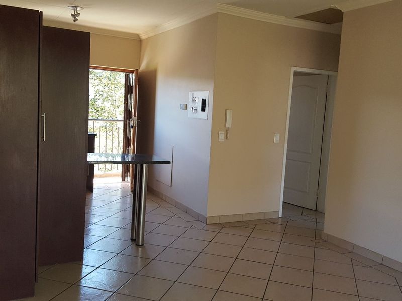 Open plan living area featuring tiled flooring, a built-in cupboard, breakfast bar, and access to a balcony.