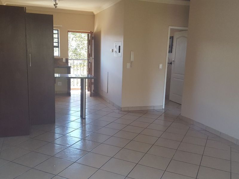An open-plan living area featuring tiled flooring, built-in storage, and direct access to a balcony, providing a functional and versatile space.
