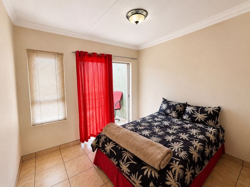 A bedroom featuring tiled flooring, a ceiling light fixture, and a sliding glass door providing access to an outdoor balcony area.
