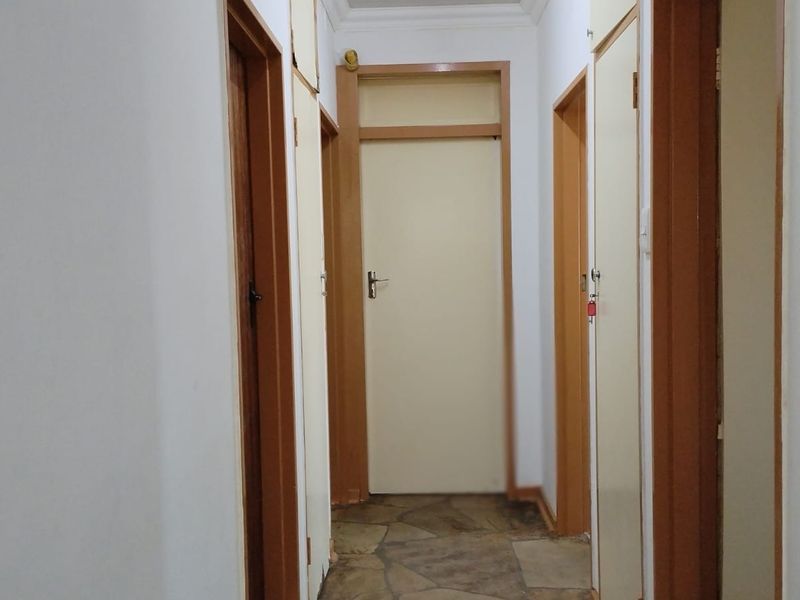 A functional hallway featuring stone flooring and multiple built-in storage cupboards with timber frames.