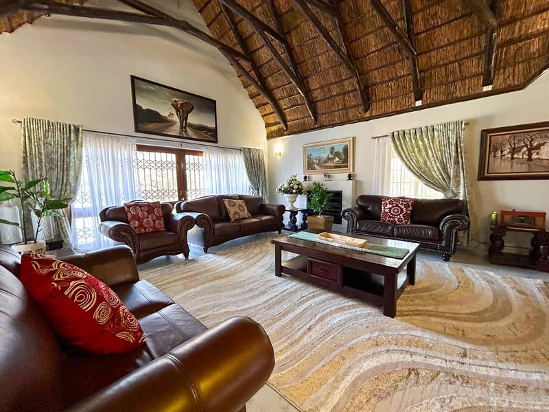 Spacious living room featuring a high vaulted thatched roof with exposed timber rafters and a built-in fireplace.