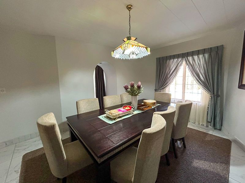 A well-lit dining room featuring tiled flooring, an arched doorway, and a decorative pendant light fixture.