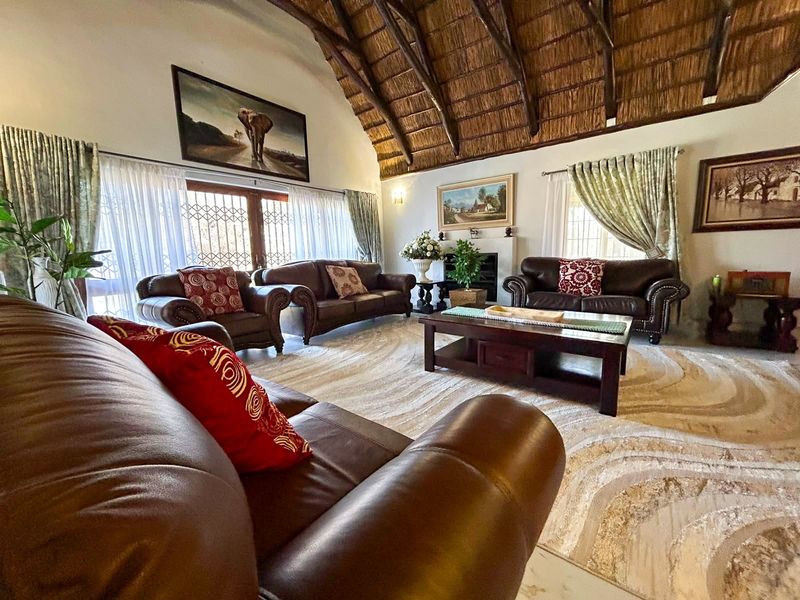 Spacious living room featuring a high vaulted thatched ceiling with exposed timber rafters and a cozy fireplace.