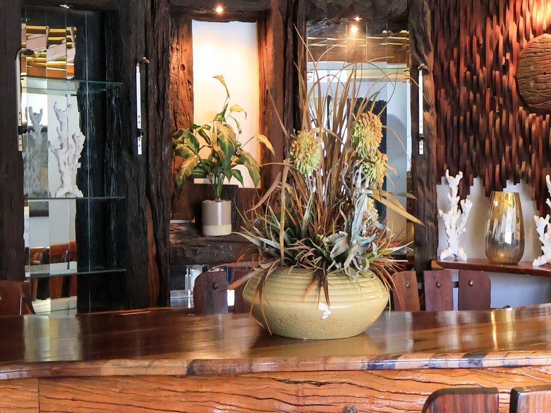 A custom-crafted wooden bar area featuring intricate timber detailing, integrated display shelving, and ambient recessed lighting.