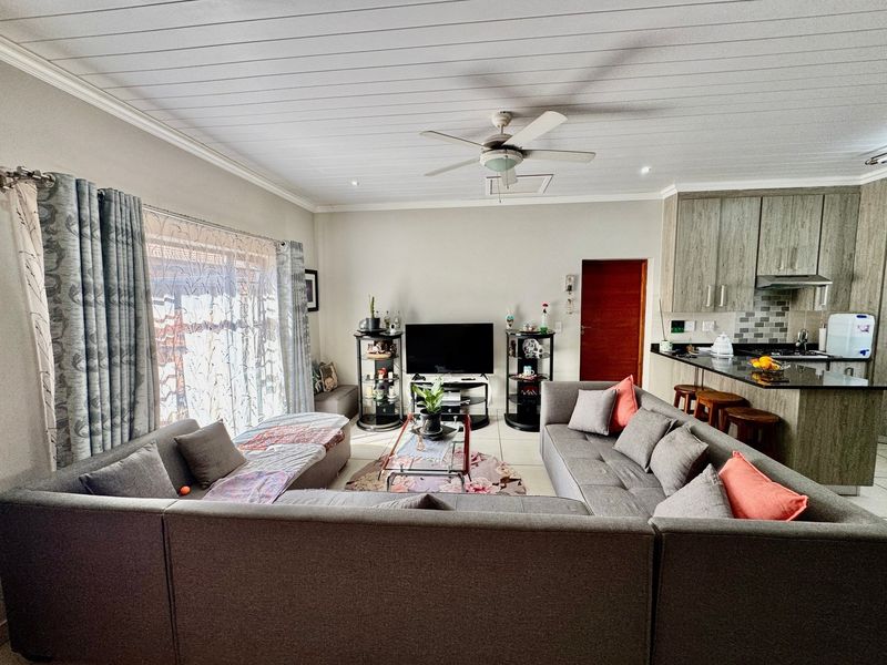 Open-plan living area featuring a modern kitchen with granite countertops, tiled flooring, and a ceiling fan, creating a functional and connected living space.
