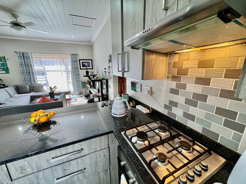 Open-plan kitchen featuring granite countertops, gas hob, extractor fan, and built-in oven, seamlessly flowing into the adjacent living area.