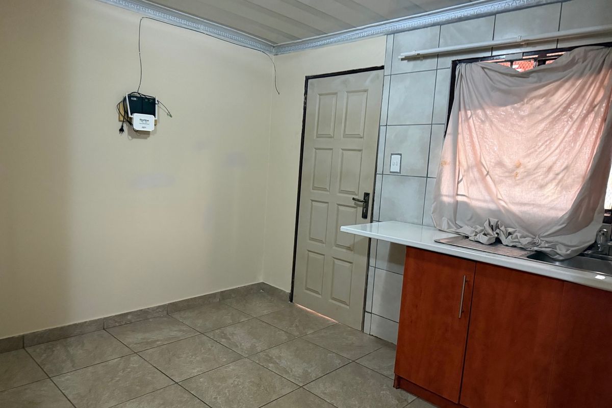A functional kitchen area featuring tiled flooring, built-in cabinetry with a stainless steel sink, and direct access to an exterior door.