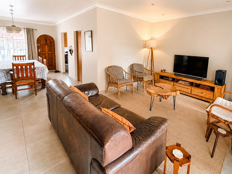 Spacious open-plan living and dining area featuring neutral wall tones, tiled flooring, and recessed lighting, creating a comfortable and functional layout.
