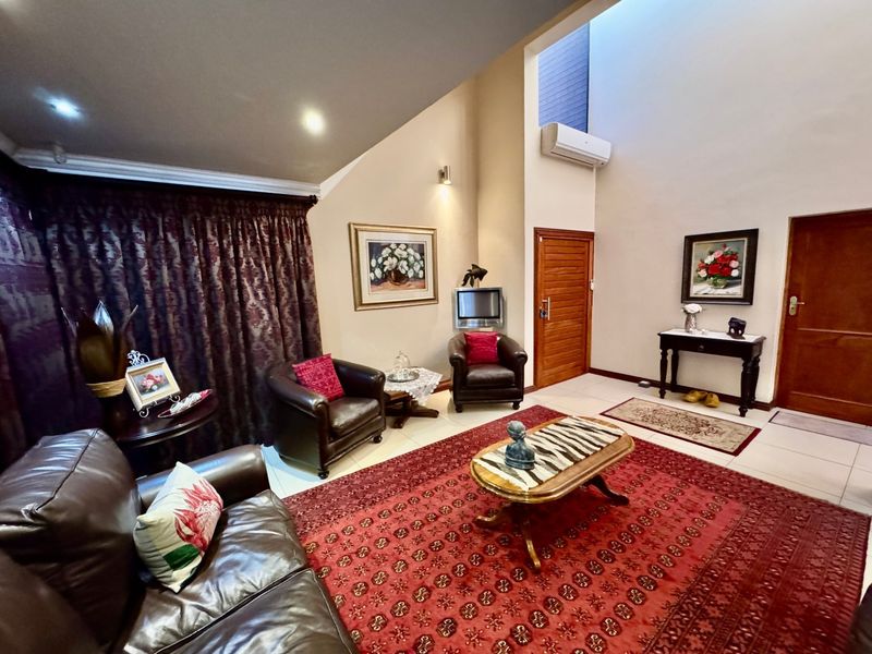 Spacious living room featuring a high vaulted ceiling, tiled flooring, and a wall-mounted air conditioning unit.