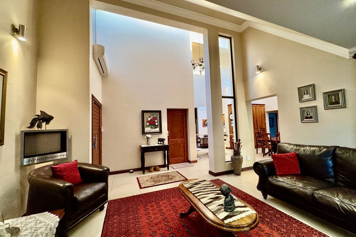 Spacious living room featuring high vaulted ceilings, a skylight, tiled flooring, and a built-in fireplace, creating an open and airy atmosphere.