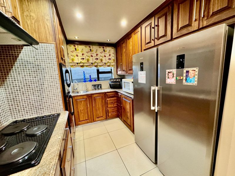 A functional kitchen featuring warm wooden cabinetry, granite countertops, mosaic tile backsplash, and stainless steel appliances, offering a classic and well-maintained cooking space.