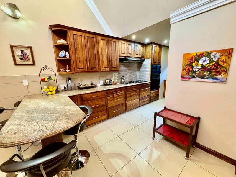 A well-maintained kitchen featuring warm wooden cabinetry, granite countertops, a breakfast nook, and built-in appliances including an oven and gas hob.