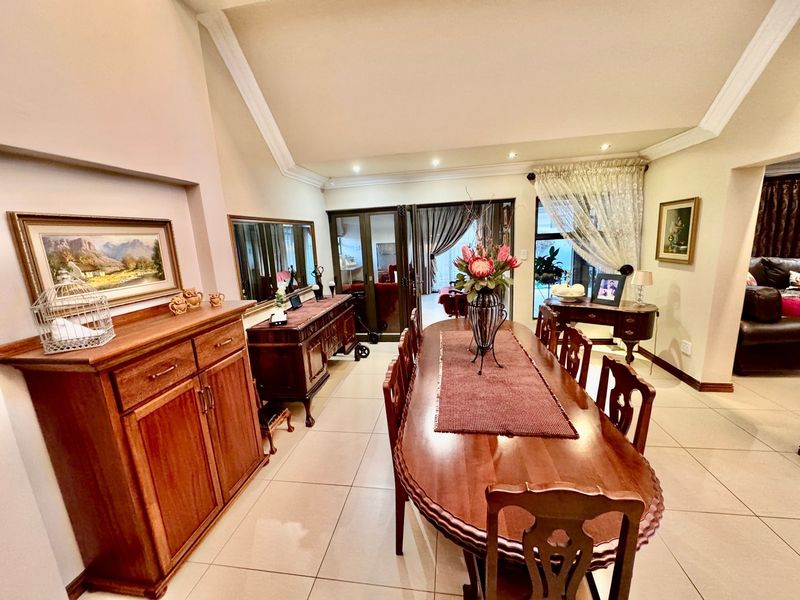 Spacious dining room featuring vaulted ceilings, recessed lighting, tiled flooring, and large sliding glass doors providing access to the outdoor area.