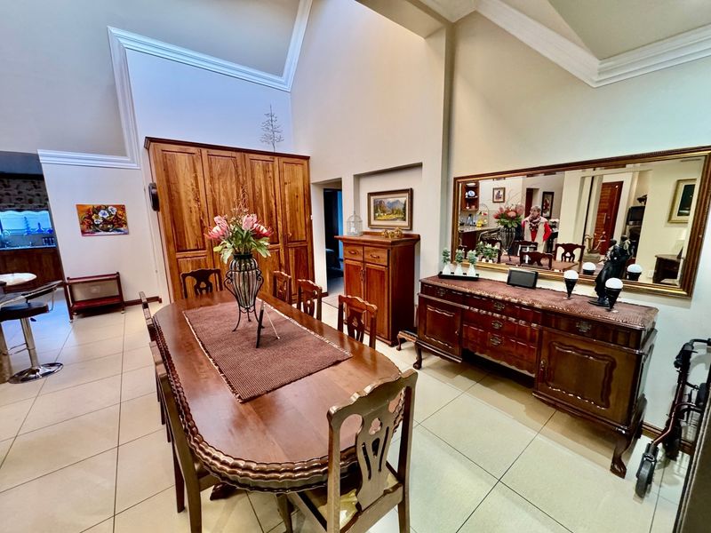 Spacious dining room featuring high vaulted ceilings, crown molding, and neutral tiled flooring, providing an open and airy atmosphere for formal entertaining.
