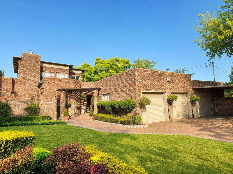 A well-maintained face brick residence featuring a double garage, paved driveway, and an inviting entrance with a timber pergola.