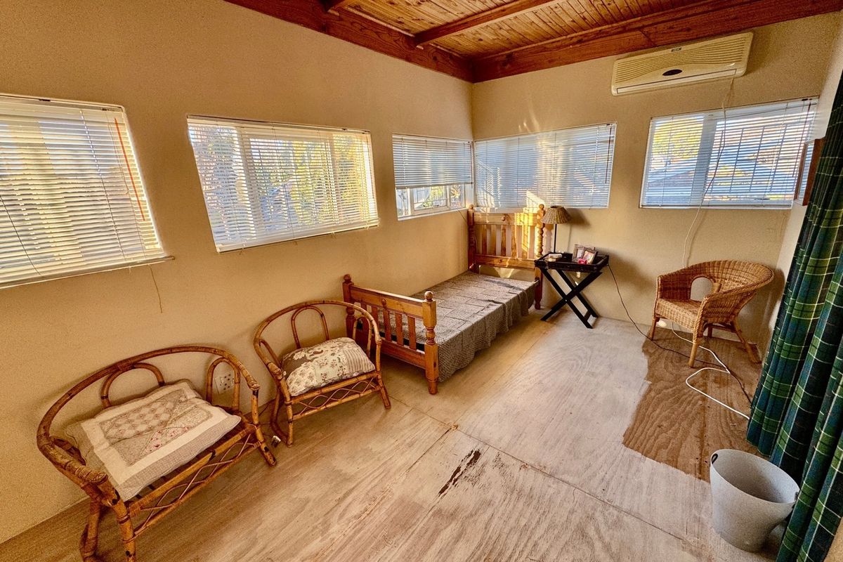 A bedroom featuring a timber ceiling, split-system air conditioning, and multiple windows with venetian blinds. The flooring shows significant signs of wear.