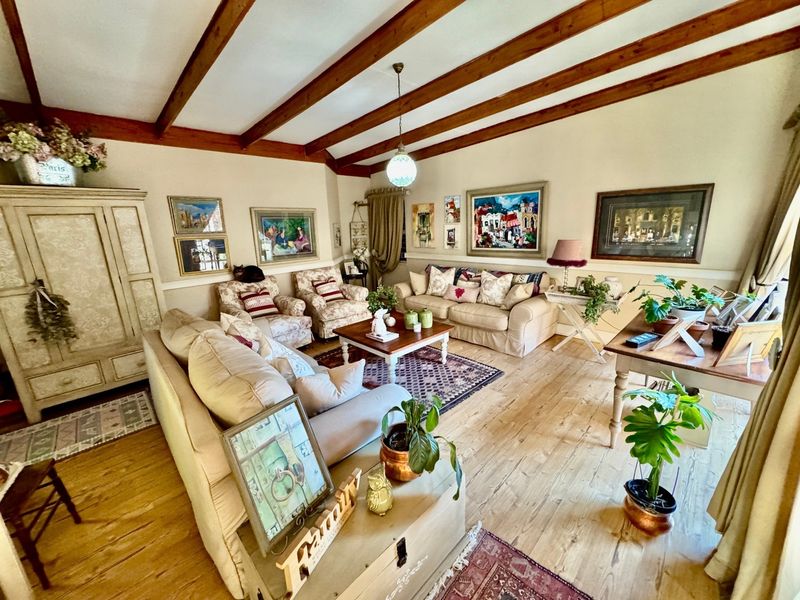 A cozy living room featuring exposed timber ceiling beams, hardwood flooring, and classic wainscoting, creating a warm and inviting atmosphere.