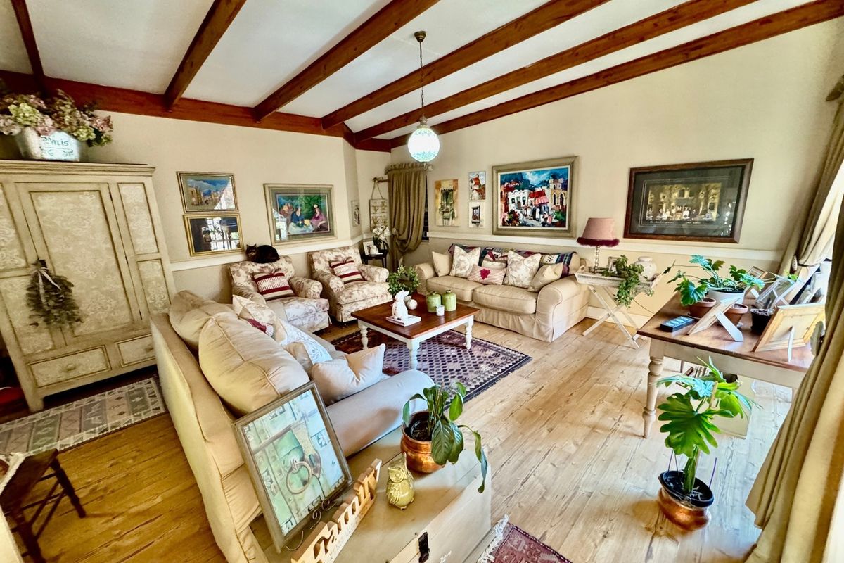 A cozy living room featuring exposed timber ceiling beams, hardwood flooring, and classic wainscoting, creating a warm and inviting atmosphere.