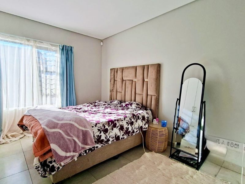 A well-lit bedroom featuring neutral wall finishes and tiled flooring, providing a comfortable and functional sleeping space.