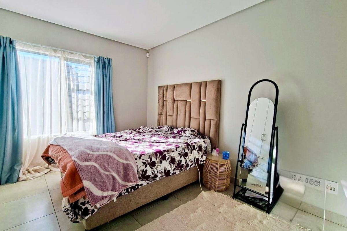 A well-lit bedroom featuring neutral wall finishes and tiled flooring, providing a comfortable and functional sleeping space.