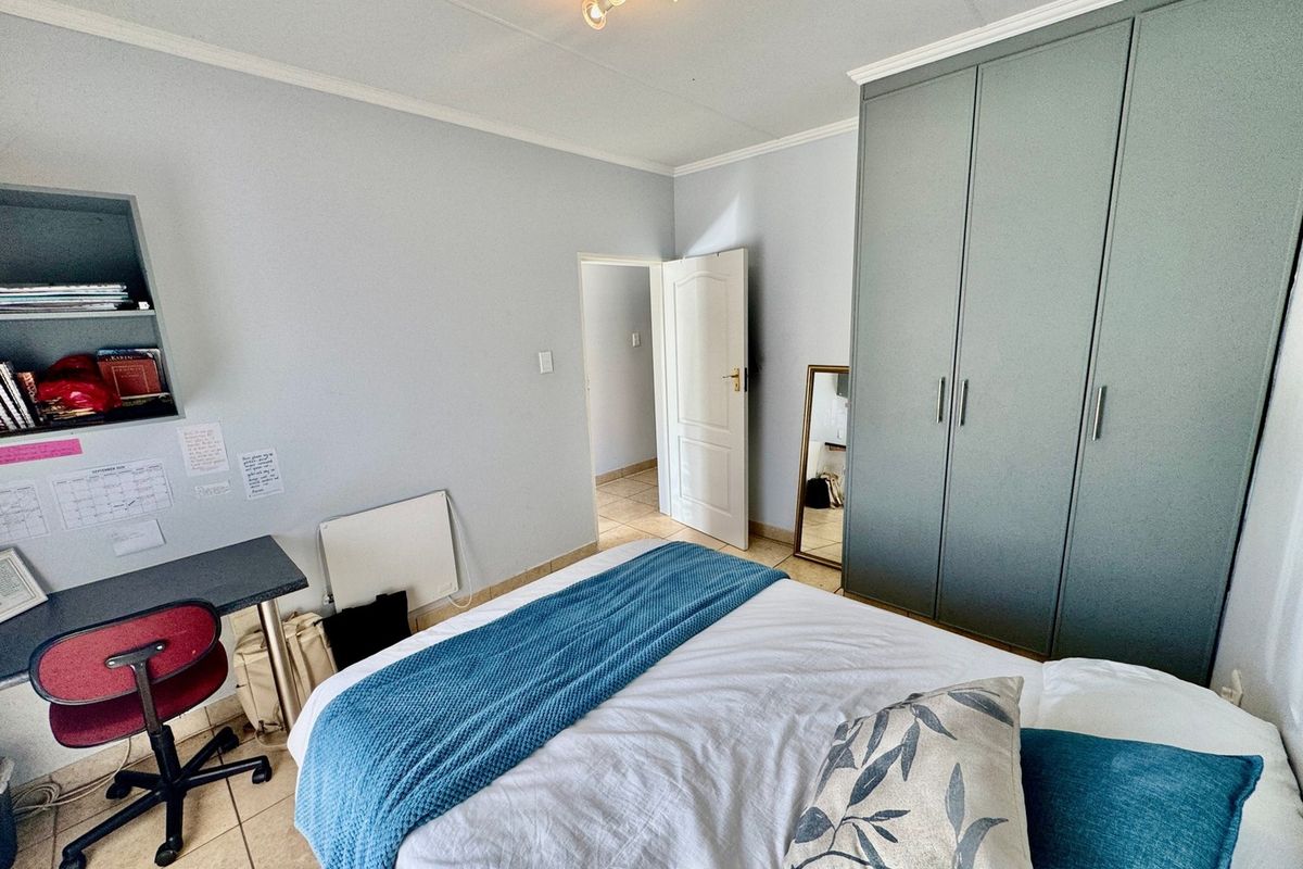 A well-maintained bedroom featuring built-in cupboards, tiled flooring, and a functional layout with integrated shelving.