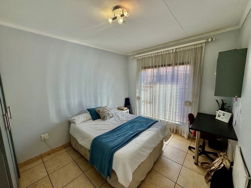 A functional bedroom featuring tiled flooring, a built-in wardrobe, and a ceiling-mounted light fixture, offering a practical living space.
