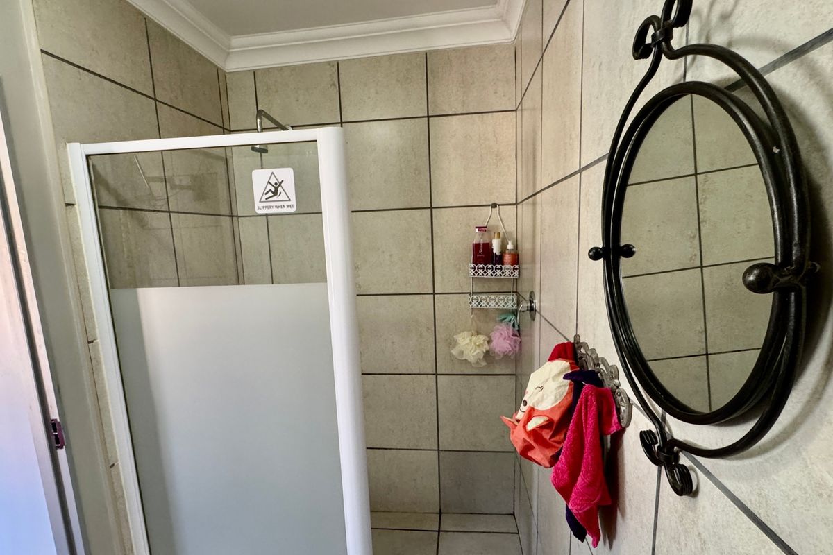 A functional bathroom featuring a shower enclosure with tiled walls and flooring, providing a clean and practical space.