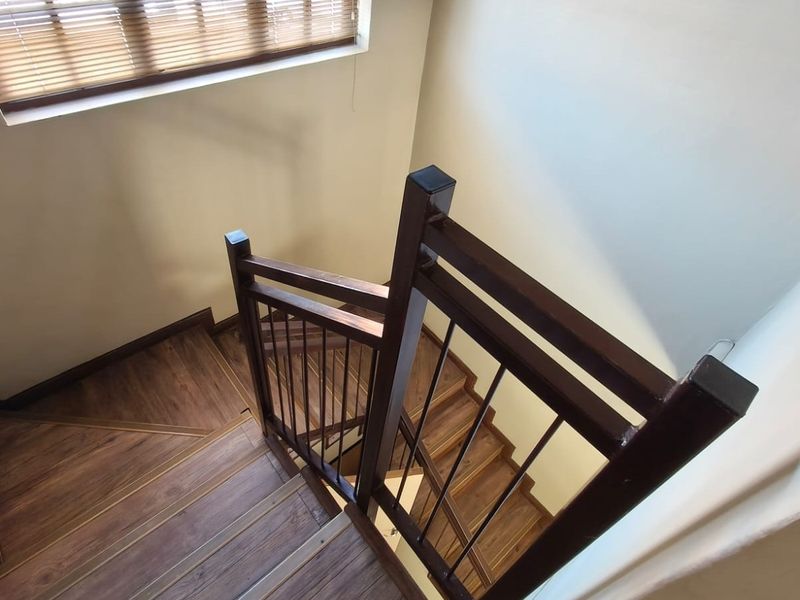 A well-maintained staircase featuring wooden treads and a sturdy metal balustrade, illuminated by natural light through a window with venetian blinds.