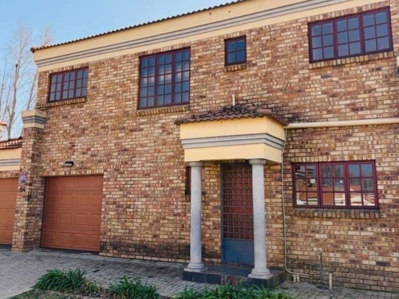 Front elevation of a double-story townhouse featuring a face-brick facade, double garage, and a covered entrance porch with decorative columns.