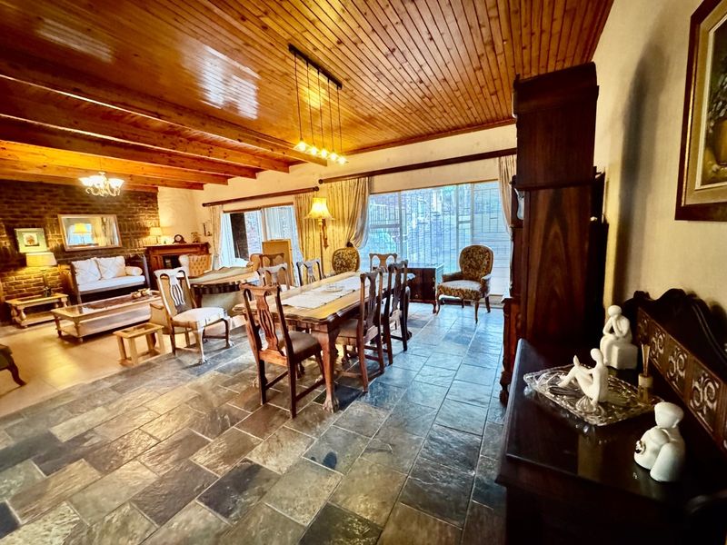 Spacious open-plan living and dining area featuring rustic slate flooring, a warm timber-clad ceiling, and a characterful brick feature wall.