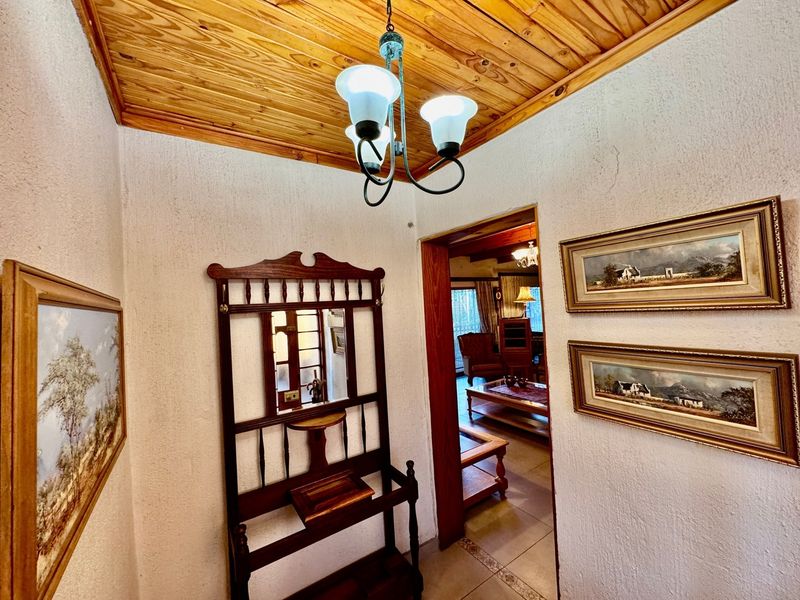 A welcoming entrance hallway featuring a warm timber ceiling, textured walls, and tiled flooring, leading through to the main living area.
