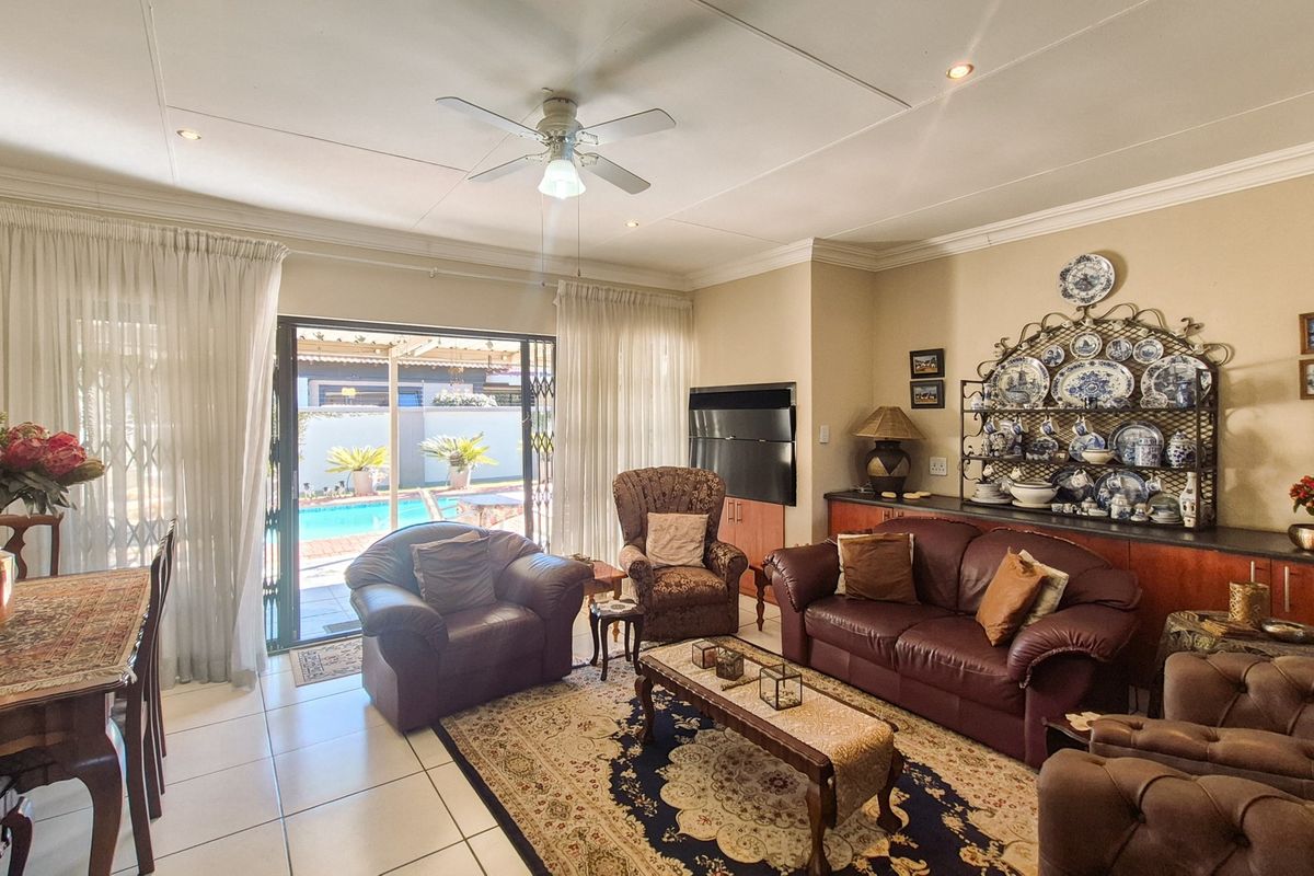 Spacious living room featuring tiled flooring, recessed lighting, a ceiling fan, and built-in cabinetry, with direct access to the outdoor pool area.