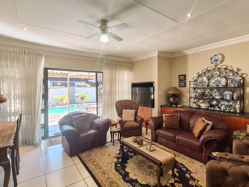 Spacious living room featuring tiled flooring, recessed lighting, a ceiling fan, and built-in cabinetry, with direct access to the outdoor pool area.
