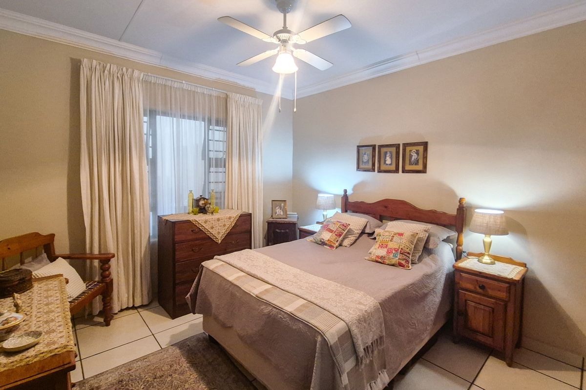A well-lit bedroom featuring tiled flooring, a ceiling fan, and built-in storage, offering a comfortable and functional living space.