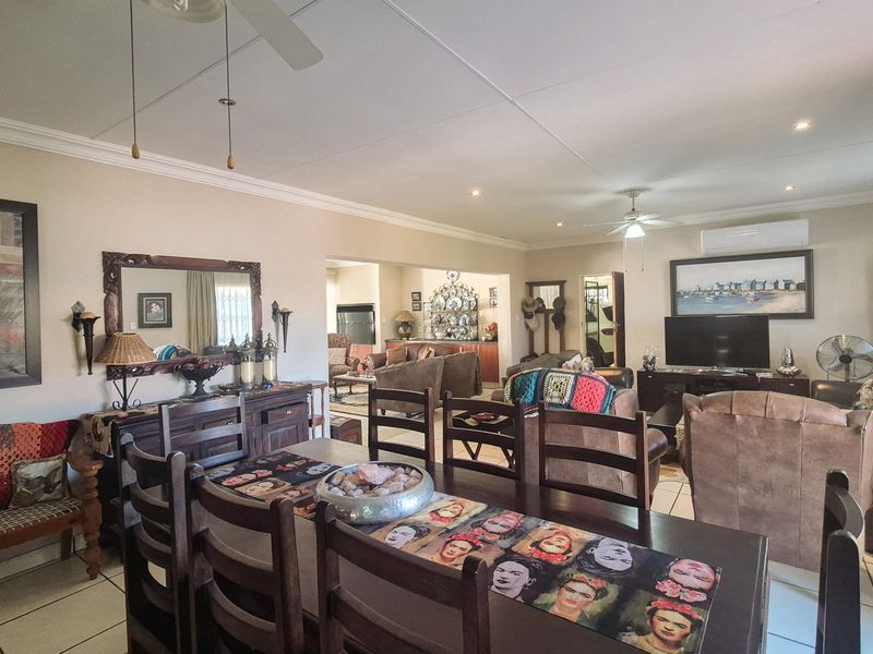 Spacious open-plan living and dining area featuring tiled flooring, ceiling fans, and split-system air conditioning, offering a versatile layout for family living.