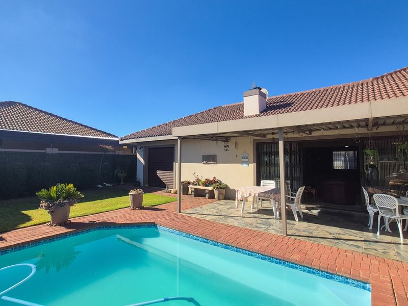 Outdoor entertainment area featuring a swimming pool with brick coping and a spacious covered patio with tiled flooring.