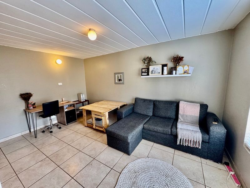 A living room featuring tiled flooring and a tongue and groove ceiling, providing a functional space with neutral wall tones.