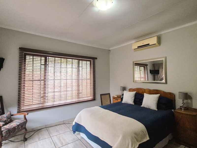 A bedroom featuring tiled flooring, an air conditioning unit, and venetian blinds on the window.