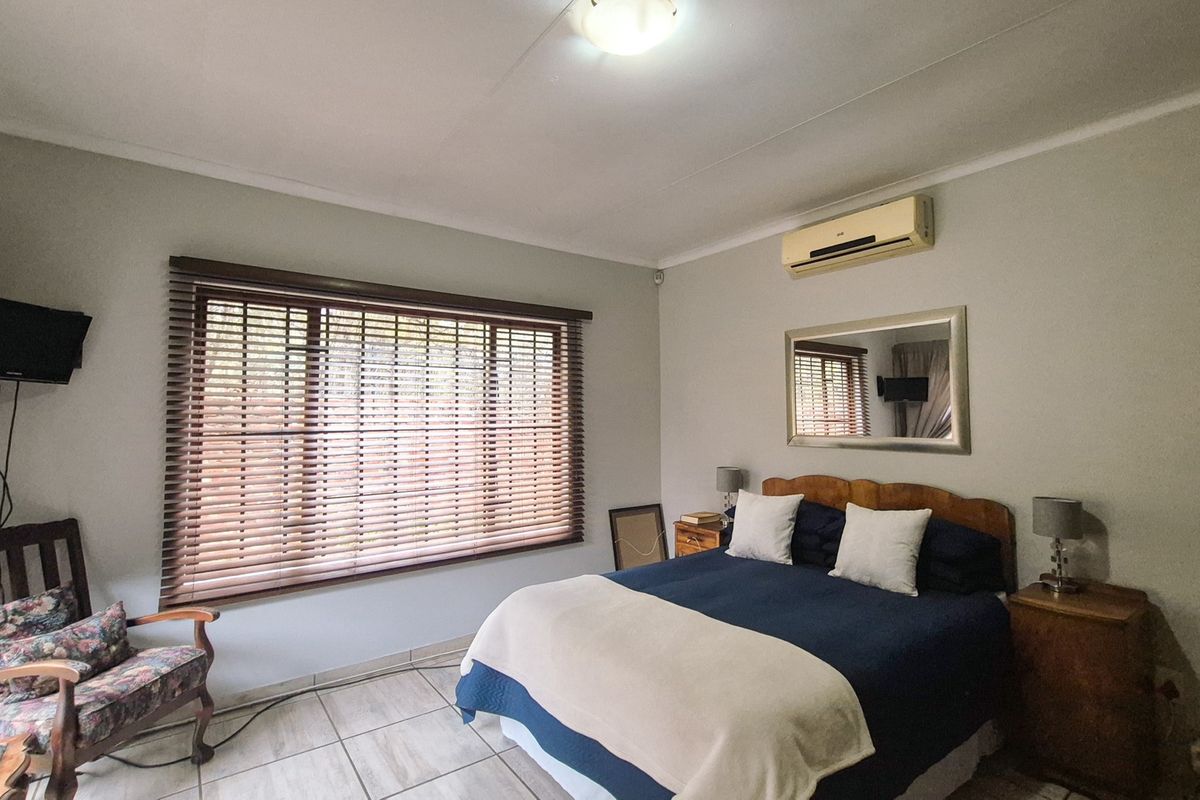 A bedroom featuring tiled flooring, an air conditioning unit, and venetian blinds on the window.