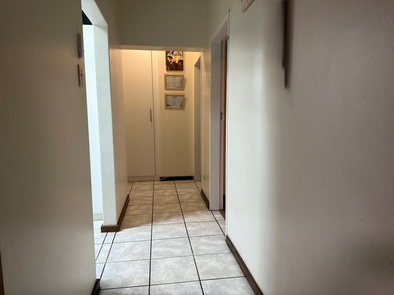 A functional hallway featuring tiled flooring and a built-in storage cupboard, providing access to other areas of the apartment.