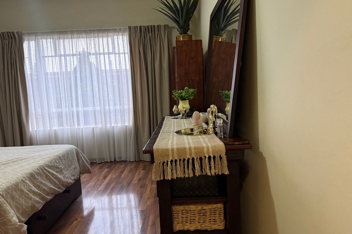 A bedroom featuring laminate flooring and large windows with curtain tracks, providing natural light to the space.