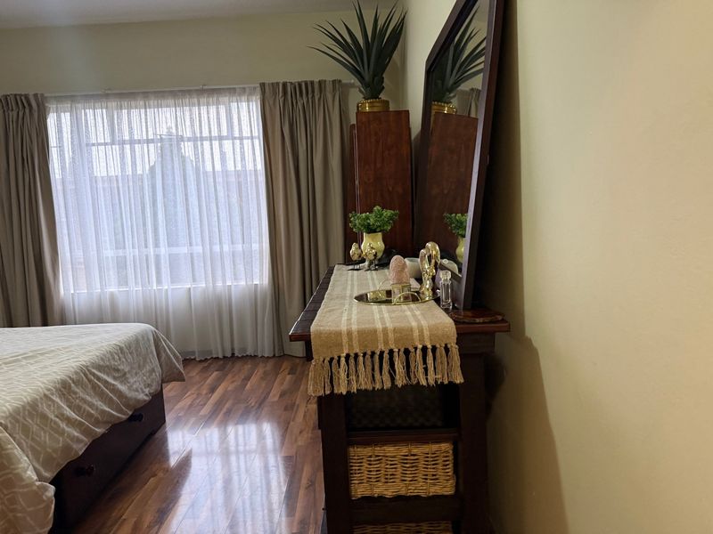 A bedroom featuring laminate flooring and large windows with curtain tracks, providing natural light to the space.