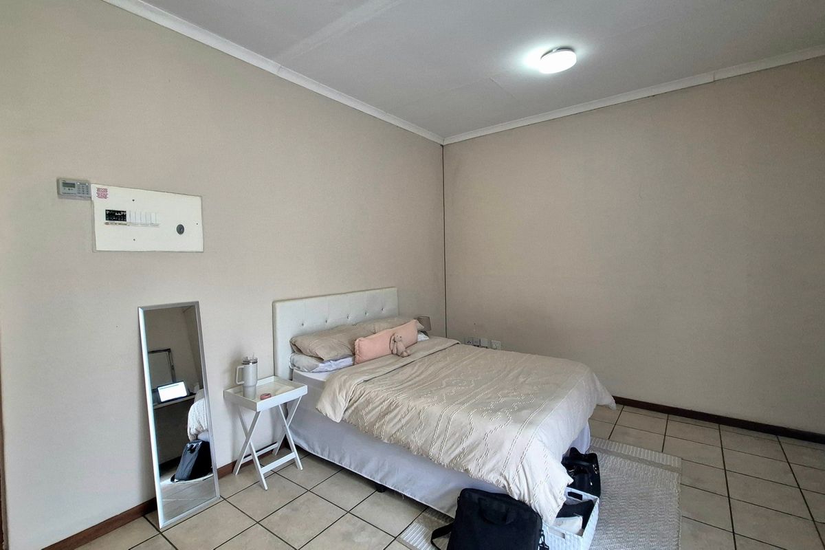 A simple bedroom featuring neutral wall tones and tiled flooring, providing a functional and blank canvas for potential interior design updates.