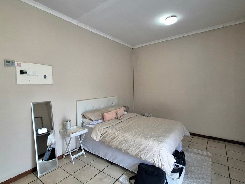 A simple bedroom featuring neutral wall tones and tiled flooring, providing a functional and blank canvas for potential interior design updates.